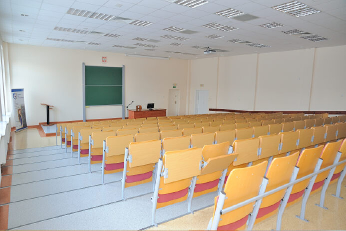 Sala B107 - widok z tyłu na amfiteatralne rzędy siedzeń i stanowisko prowadzącego przy tablicy.