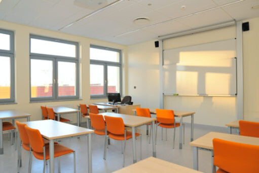 Sala A308 - stoły w układzie szkolnym oraz stanowisko komputerowe przy tablicy.