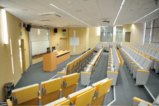 Sala A407 - amfiteatralne rzędy foteli z pulpitami, mównica i stanowisko prowadzącego.