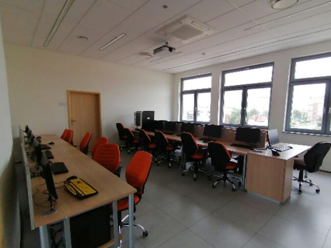 Pracownia A420 - stanowiska komputerowe wzdłuż ścian i pod oknami oraz projektor sufitowy.